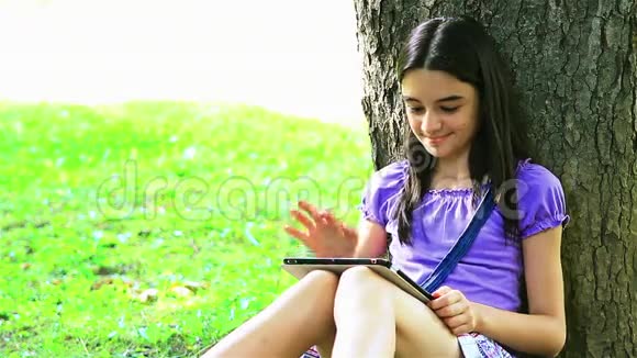公园里使用数码平板电脑的少女视频的预览图