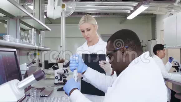科学家和在实验室工作的学生医生带教实习生做分析研究实验室工具显微镜视频的预览图