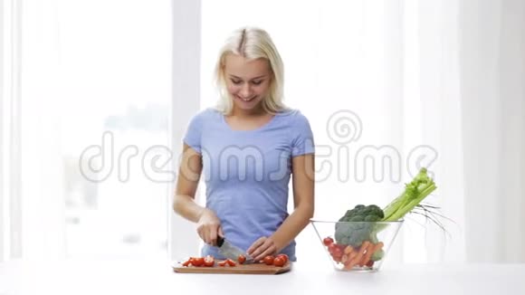 微笑的年轻女子在家里切西红柿视频的预览图