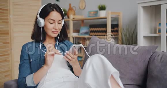 美丽的年轻女性使用智能手机通过耳机听音乐视频的预览图