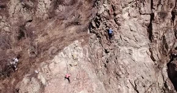 登山者爬上岩石女孩和男孩爬上岩石攀岩课视频的预览图