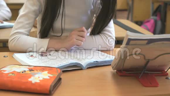 坐在学校课桌上的女学生读课本视频的预览图