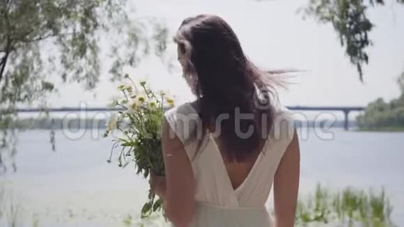 肖像可爱的年轻女孩留着长长的黑发穿着一件白色的站在上面视频的预览图