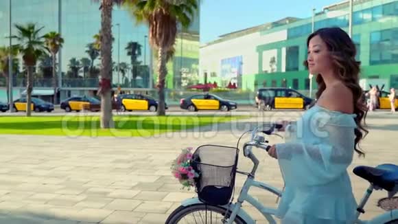 穿着蓝色衣服的亚洲模特骑着白色自行车在绿色公园里视频的预览图