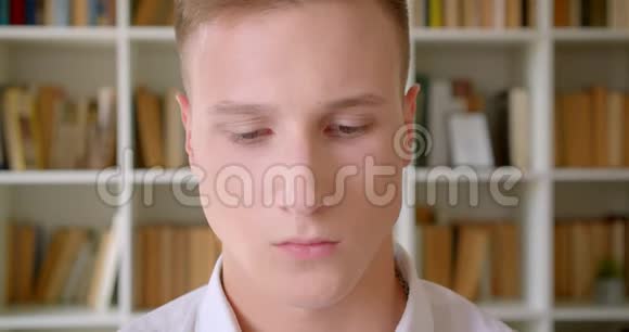 年轻英俊的白种人男学生在大学图书馆看镜头的特写镜头视频的预览图