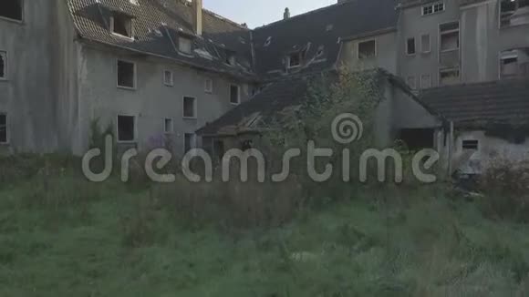 空中拍摄的一个鬼城缓慢上升到破旧的一排房子屋顶和烟囱视频的预览图