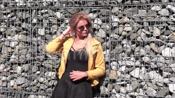 穿着黄色夹克和太阳镜的金发美女视频的预览图