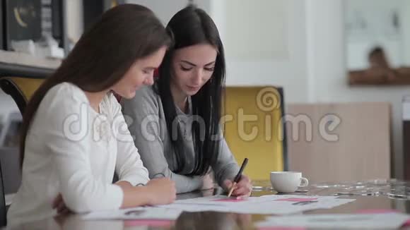两个年轻的女人坐在办公室的一张桌子旁视频的预览图