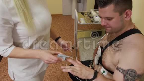 对于诊所里的病人来说一位男性护士在他的身体上放置一个装置来研究身体参数视频的预览图