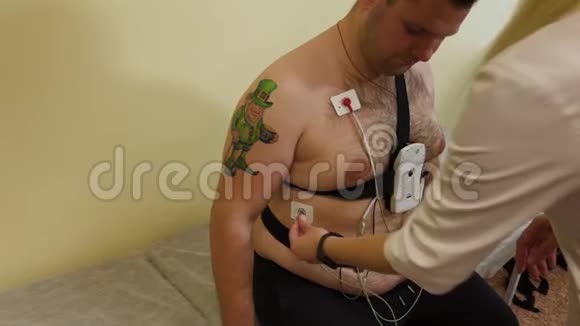 对于诊所里的病人来说一位男性护士在他的身体上放置一个装置来研究身体参数视频的预览图