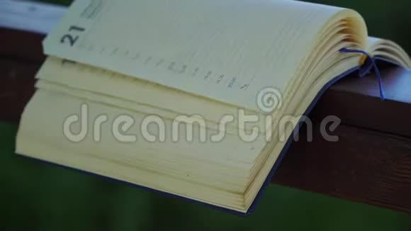 风把开着的笔记本书页在公园的木扶手上商业理念视频的预览图
