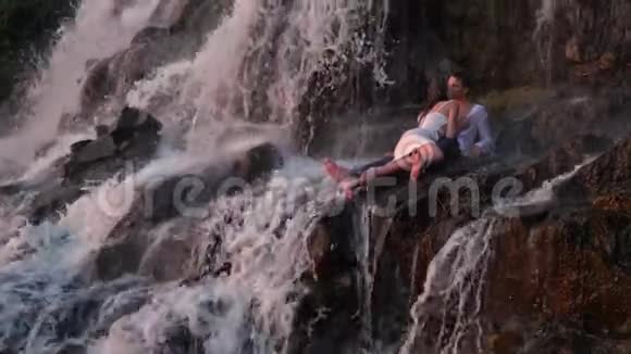 日落时分男人和女人在瀑布下接吻视频的预览图