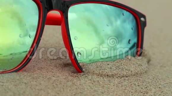 太阳镜躺在沙子上戴着墨镜反射着大海海浪和天空视频的预览图