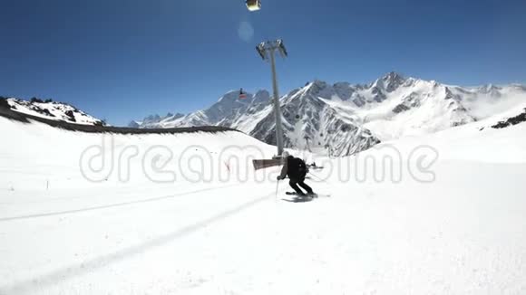 阳光明媚的一天一个身穿黑色装备戴着滑雪杆的白色头盔的宽角男滑雪者骑在雪坡上视频的预览图