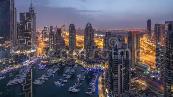 从空中俯瞰迪拜码头的夜晚到白天现代化的塔楼和道路上的交通视频的预览图