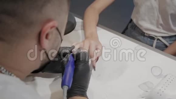专业的美甲师男人用一种特殊的指甲油清除剂从女孩身上去除旧指甲油视频的预览图