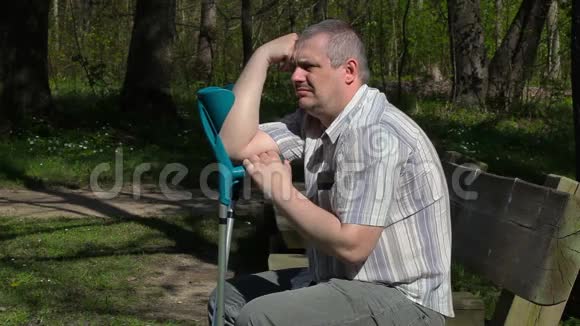 公园里坐在长凳上拄拐杖的残疾人视频的预览图