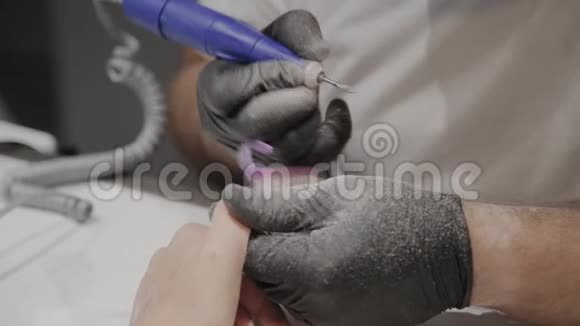 专业的美甲师男人用一种特殊的指甲油清除剂从女孩身上去除旧指甲油视频的预览图