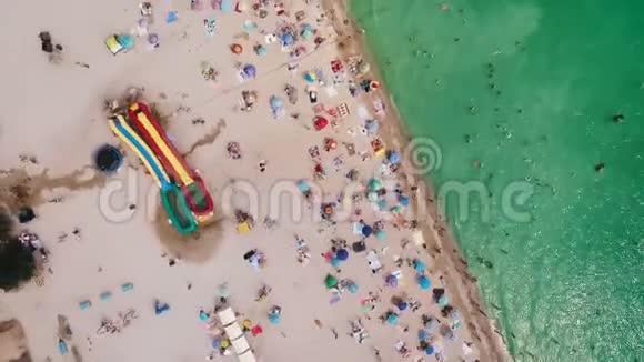 在阳光明媚的热天鸟瞰拥挤的海滩黄沙和雨伞视频的预览图