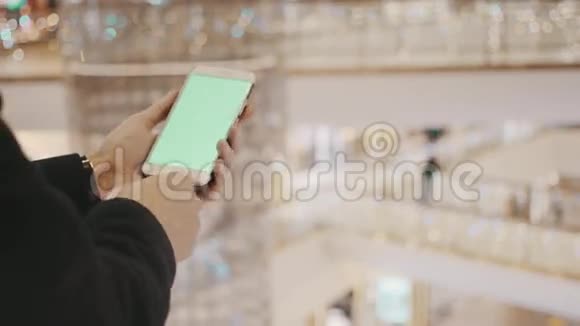 男性手使用智能手机与绿色屏幕在购物中心背景节日装饰品视频的预览图