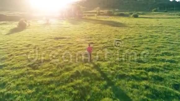 飞越运动男子跑在完美的绿色草地农村草地越野山上日落视频的预览图