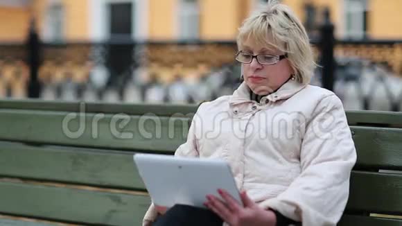 女人坐在长凳上用平板电脑有平板电脑的妇女视频的预览图