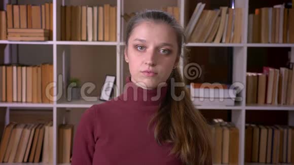 在大学图书馆室内看镜头的白种人年轻女学生特写照片视频的预览图