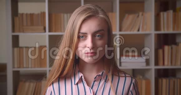 年轻漂亮的白种人女学生在大学图书馆看镜头的特写镜头视频的预览图