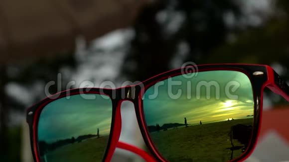 太阳落山时太阳镜躺在沙滩上戴着墨镜反射着大海海浪和天空视频的预览图