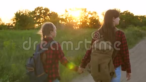 远足女孩青少年女孩旅行和牵手儿童旅行者乡村公路上的旅游女孩带背包的女孩视频的预览图