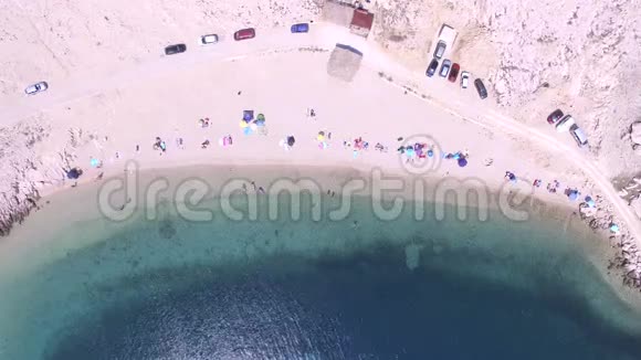在雨伞和人的头顶上飞翔在克罗地亚帕格岛的偏僻海滩上视频的预览图