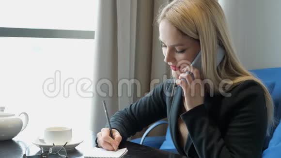 一位西装革履的年轻女商人坐在咖啡馆的桌子上视频的预览图