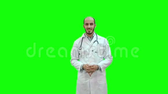 快乐的医生微笑着看着绿色屏幕上的相机Chroma键视频的预览图