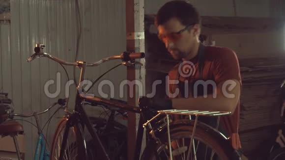 主题小商业自行车修理年轻的白种人黑发男子戴着安全眼镜手套和围裙使用手工工具修理视频的预览图