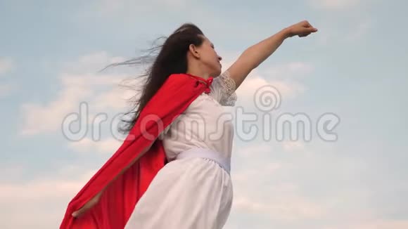美丽的超级英雄女孩站在一片红色斗篷的田野上斗篷在风中飘扬女孩梦想成为一个视频的预览图