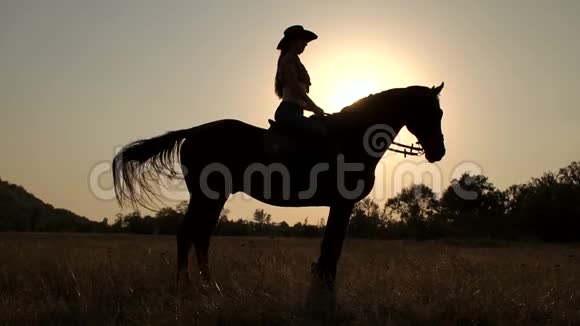日落时骑马的女人的剪影视频的预览图