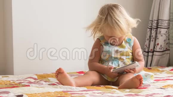 金发小女孩玩智能手机视频的预览图