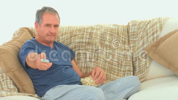 成熟的男人用爆米花看电视视频的预览图
