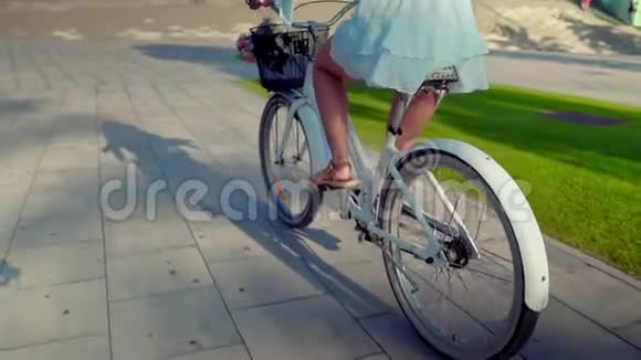 穿着蓝色衣服的亚洲模特骑着白色自行车在绿色公园里视频的预览图