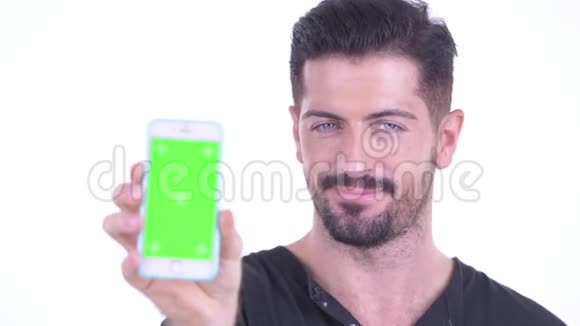 脸上洋溢着幸福的年轻英俊的胡须男展示着电话视频的预览图