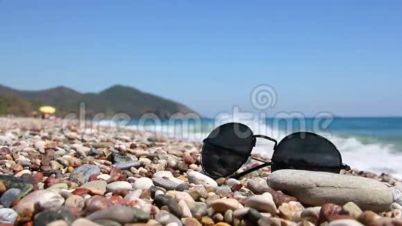 在海边的鹅卵石海滩上戴太阳镜视频的预览图