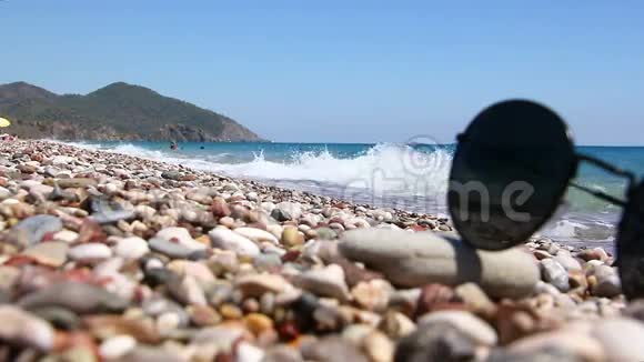 在海边的鹅卵石海滩上戴太阳镜视频的预览图
