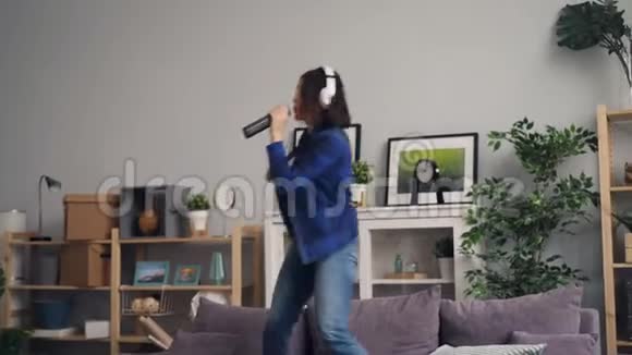 欢乐的女人在家里用耳机唱歌跳舞听音乐视频的预览图