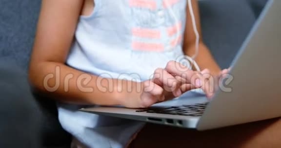 带耳机的女孩在客厅用笔记本电脑视频的预览图