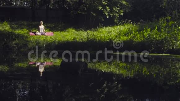 在河岸做瑜伽体式的年轻女子视频的预览图