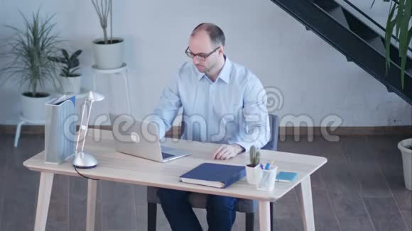 帅哥商人在办公室里用笔记本电脑工作视频的预览图