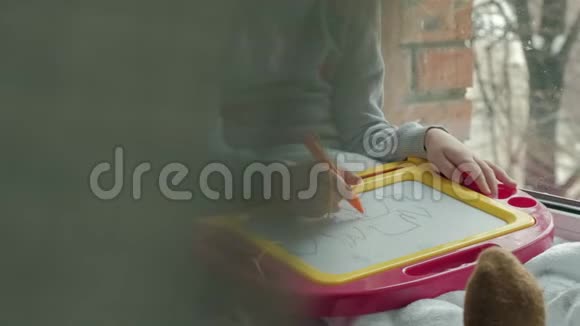 一个红色波浪发的小女孩躺在地板上画在一块磁板上教育过程的概念视频的预览图