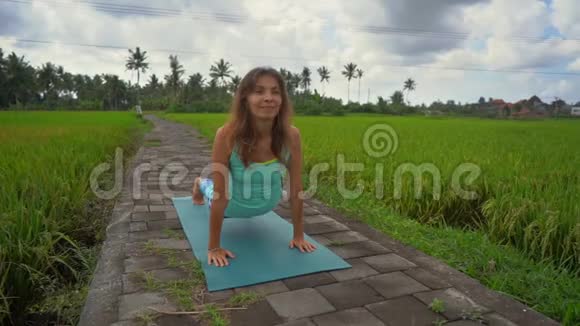 一位年轻女子在美丽的稻田里练习瑜伽的慢镜头视频的预览图