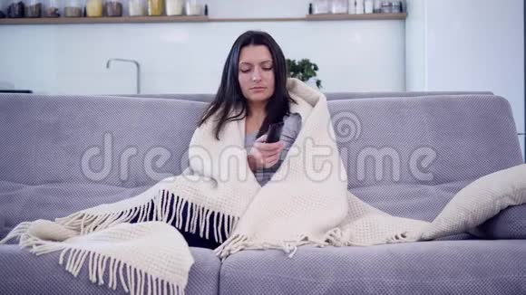 一个女人正在用毯子看电视视频的预览图