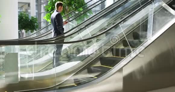 一个年轻的商人在一座现代化的大楼里的自动扶梯上视频的预览图